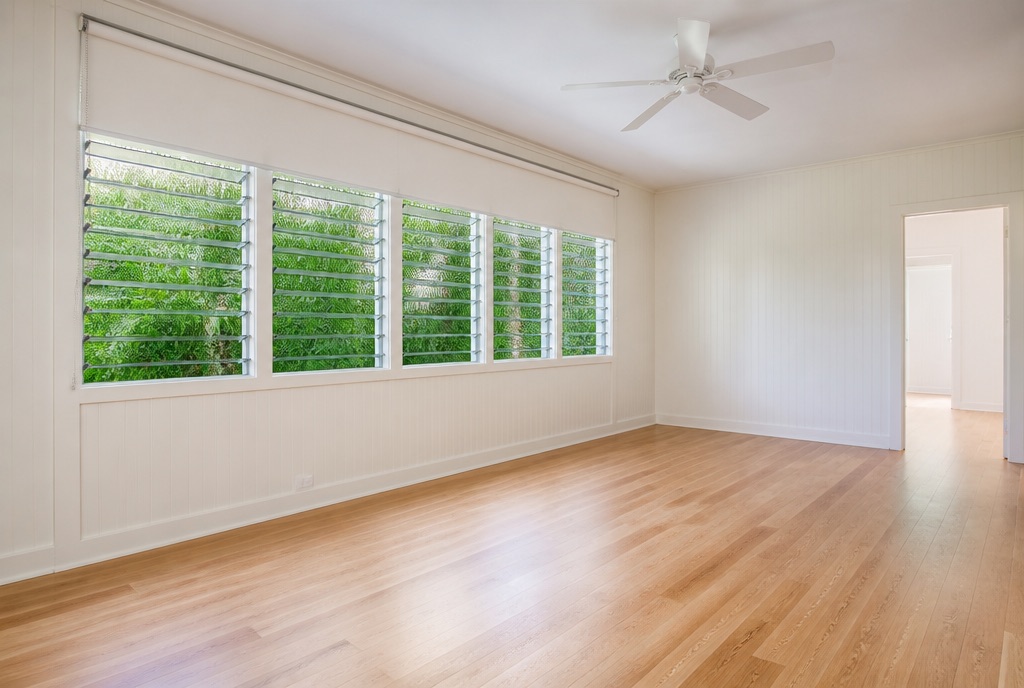 An empty Honolulu living room prepared for a new tenancy, with jalousie windows open to greenery.