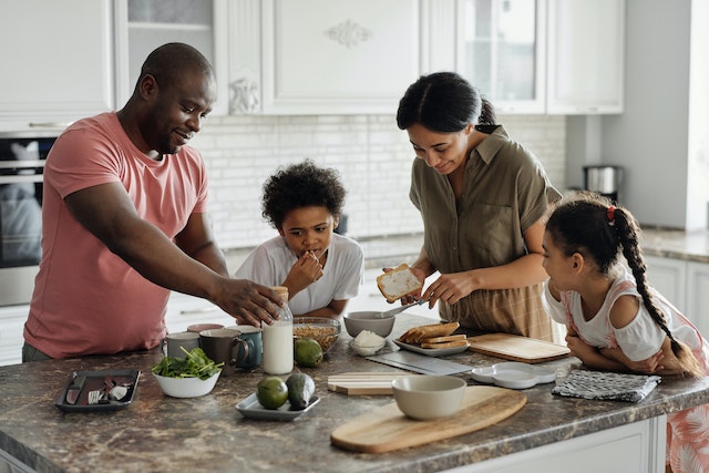 A family preparing food together at a kitchen counter.
