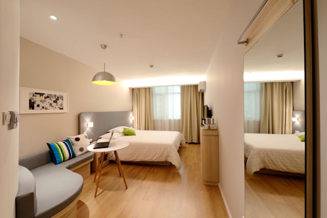 A furnished rental bedroom with neutral decor and a seating area.