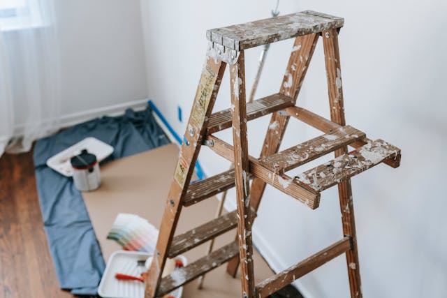 Paint cans and a step ladder in a room being repaired.