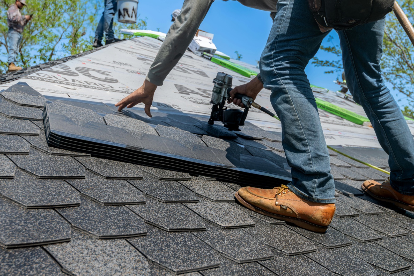 A contractor replacing shingles on a roof.