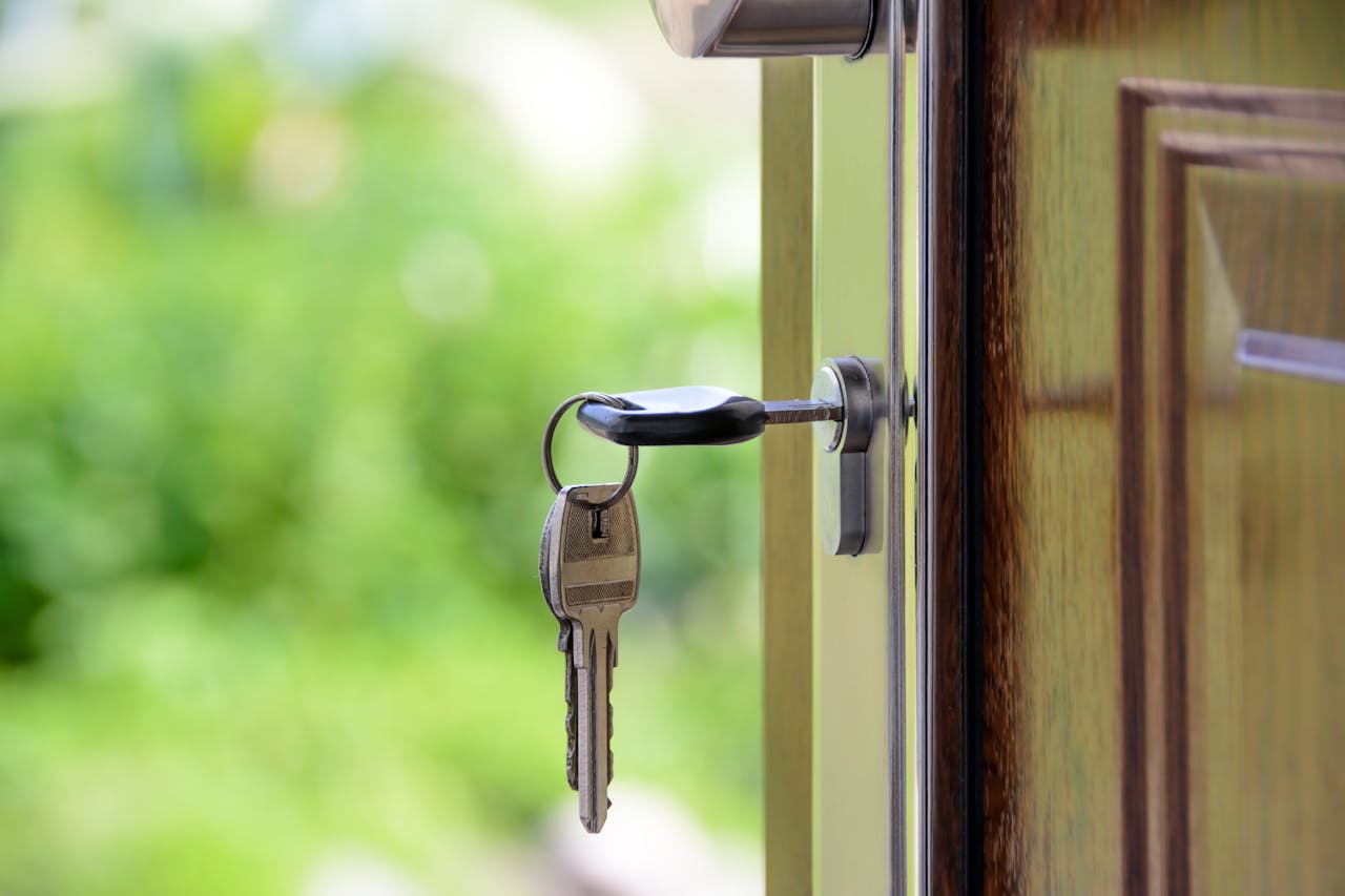 A set of keys hanging from the lock of a front door.