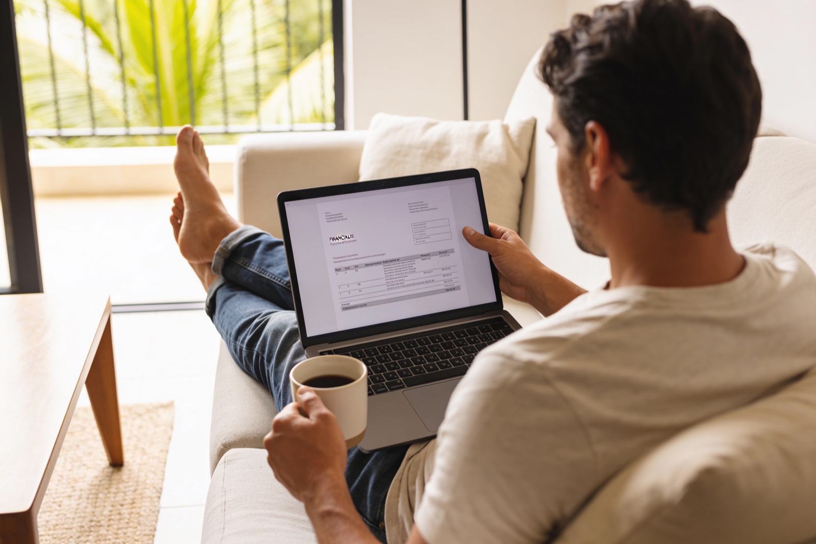 A relaxed property owner reviewing a monthly financial statement on a laptop at home
