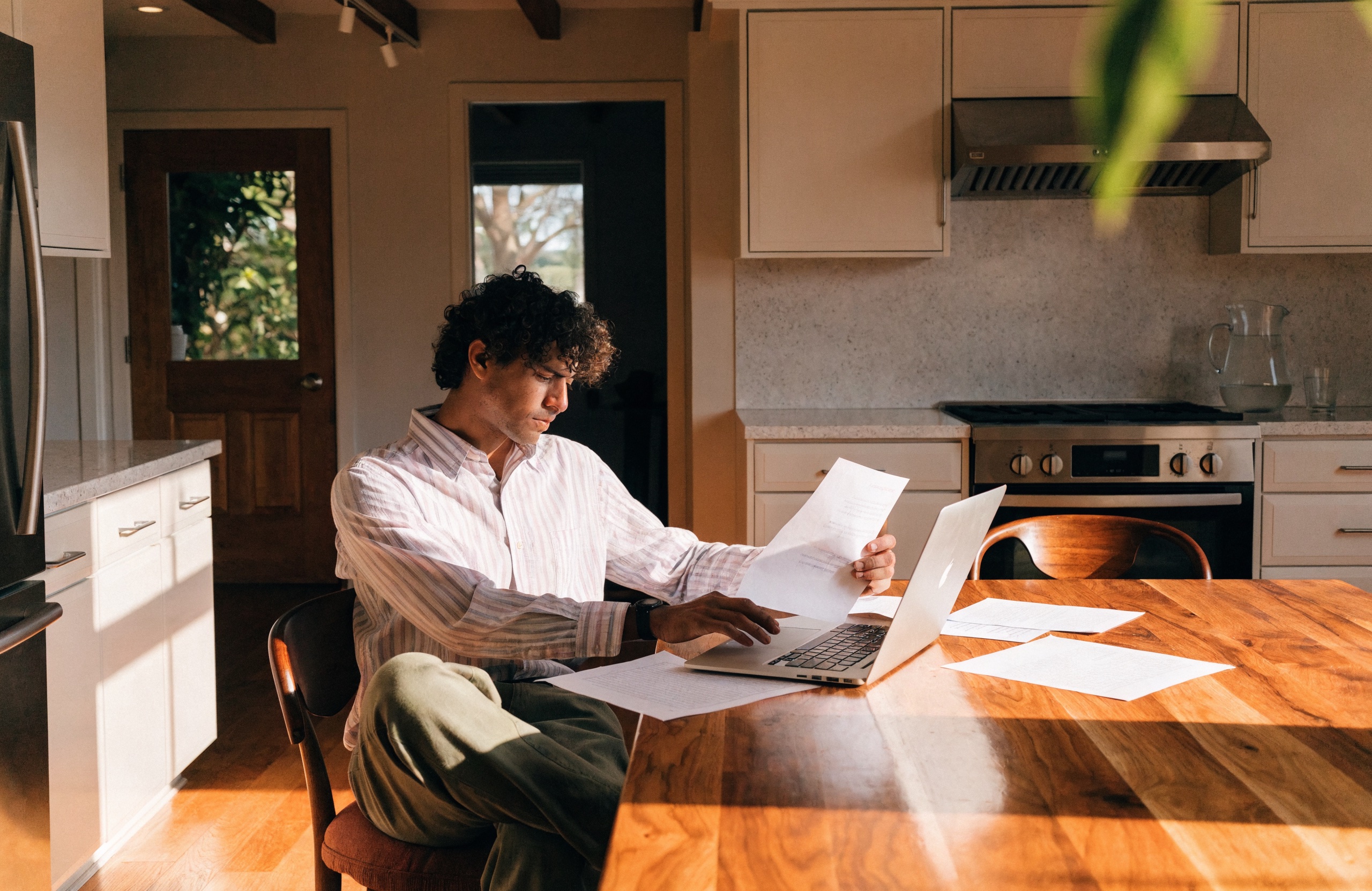 Rental property owner reviewing finances at a bright kitchen table.