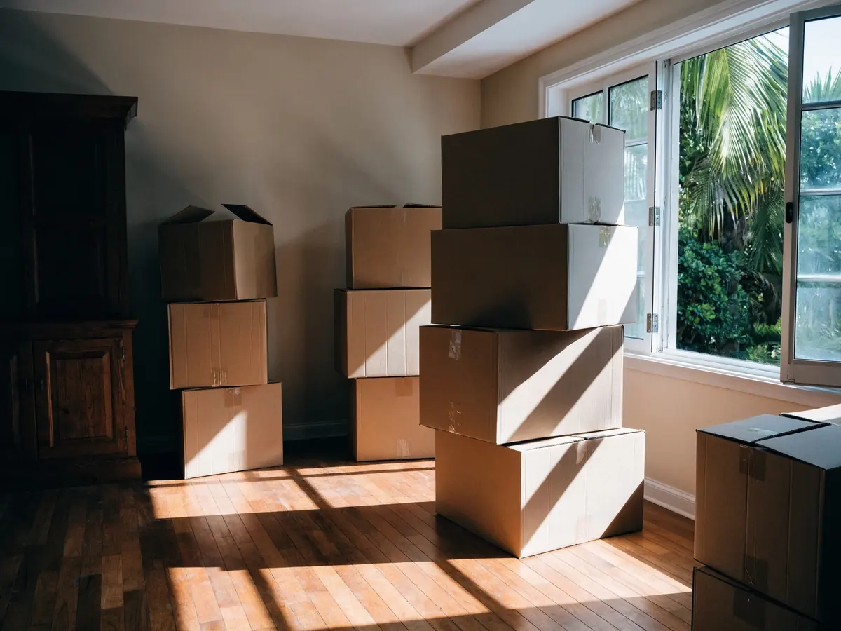 Packed moving boxes stacked in the sunlit living room of a Hawaii home